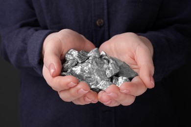 Photo of Woman with silver nuggets on black background, closeup