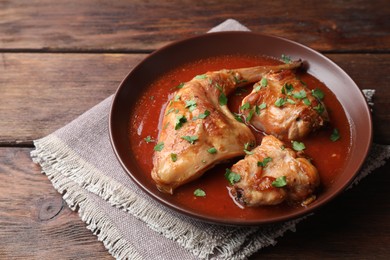 Tasty cooked rabbit meat with sauce and parsley on wooden table