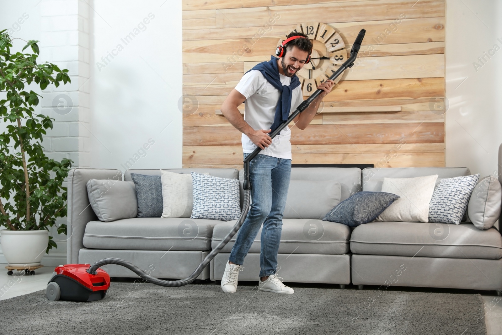 Photo of Young man having fun while vacuuming at home