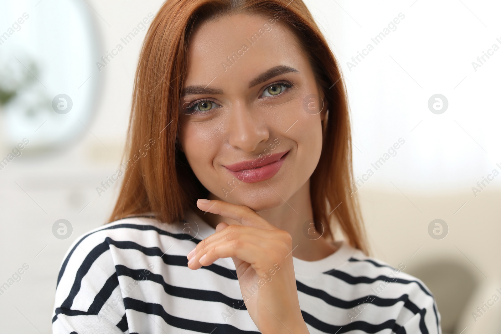 Photo of Portrait of beautiful young woman with red hair at home. Attractive happy lady looking into camera