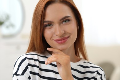 Photo of Portraitbeautiful young woman with red hair at home. Attractive happy lady looking into camera