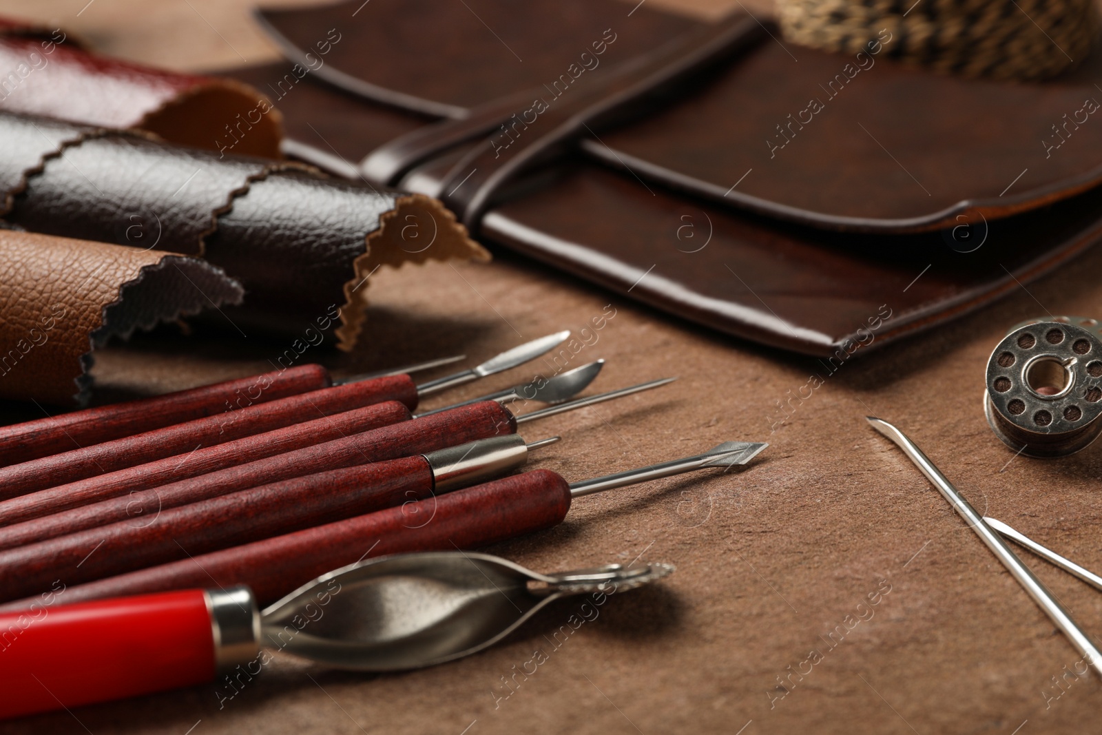 Photo of Leather samples and tools on brown table, closeup