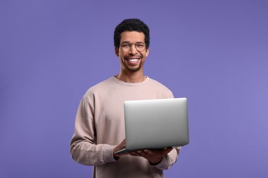 Photo of Smiling man with laptop on purple background