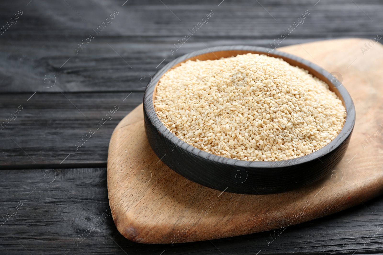 Photo of Plate with sesame seeds on black wooden table