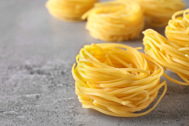 Uncooked angel hair pasta on grey table, closeup. Space for text