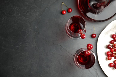 Delicious cherry wine with ripe juicy berries on grey table, flat lay. Space for text