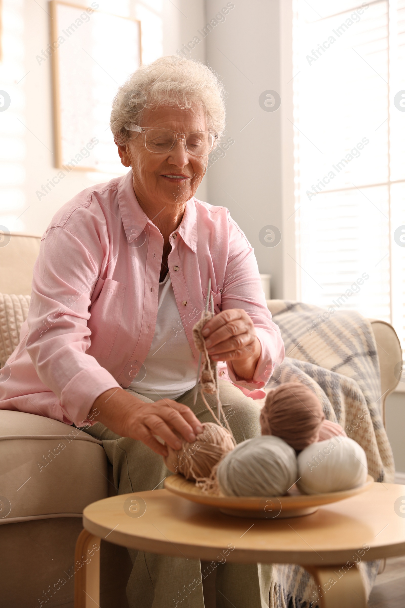 Photo of Elderly woman knitting at home. Creative hobby