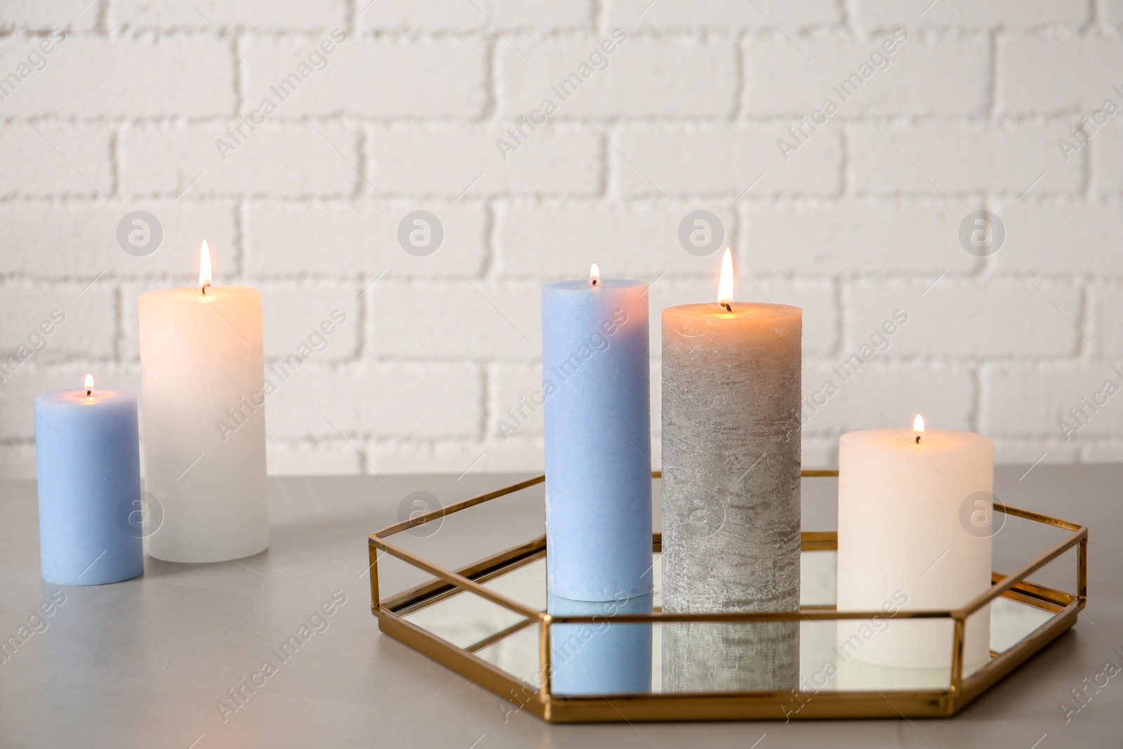 Photo of Tray with decorative candles on table against brick wall