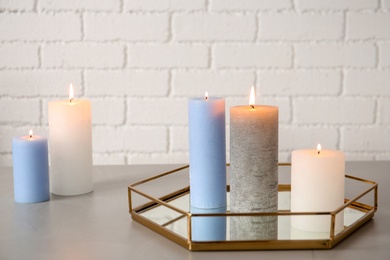 Photo of Tray with decorative candles on table against brick wall