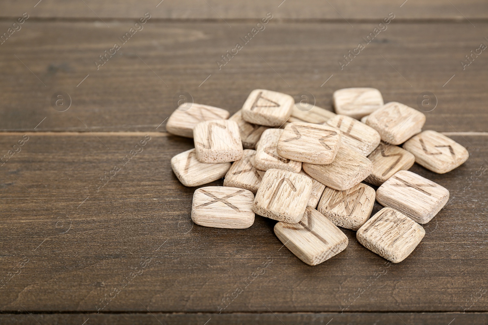 Photo of Pile of runes with different symbols on wooden table