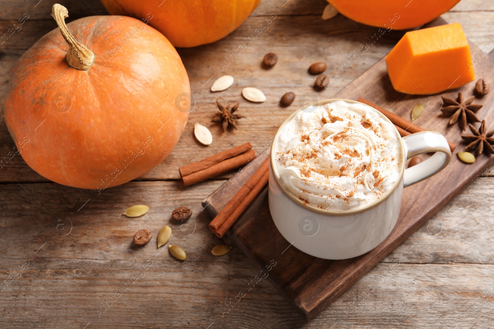 Photo of Cup with tasty pumpkin spice latte on wooden table