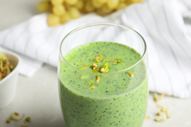 Photo of Green buckwheat smoothie on light grey table, closeup