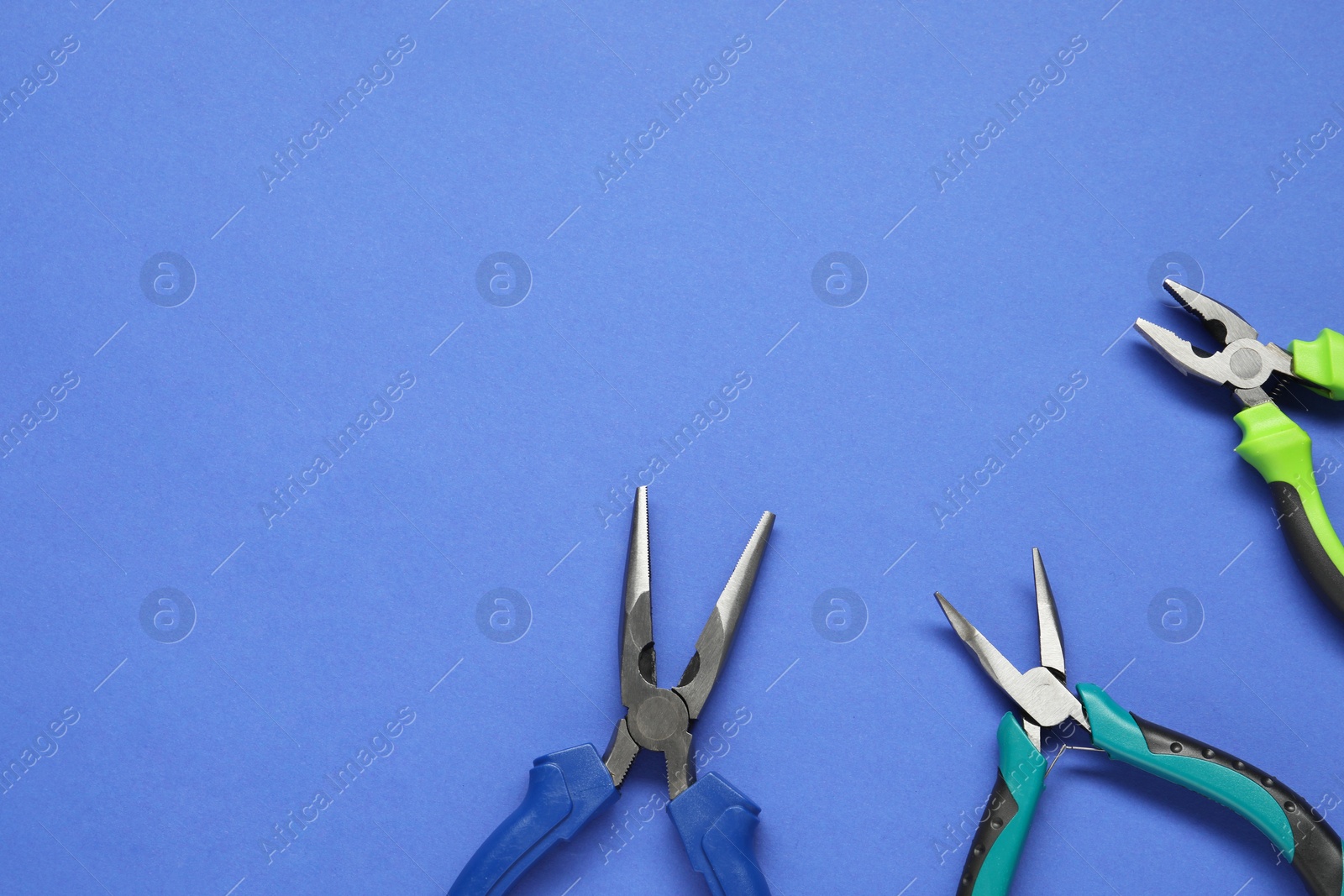 Photo of Different pliers on blue background, flat lay. Space for text