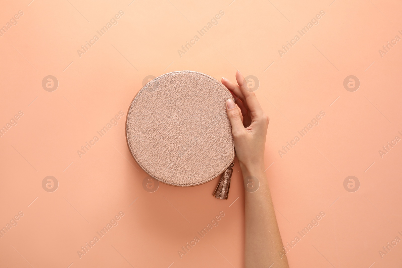 Photo of Woman holding stylish handbag on beige background, closeup