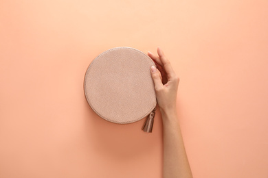 Woman holding stylish handbag on beige background, closeup