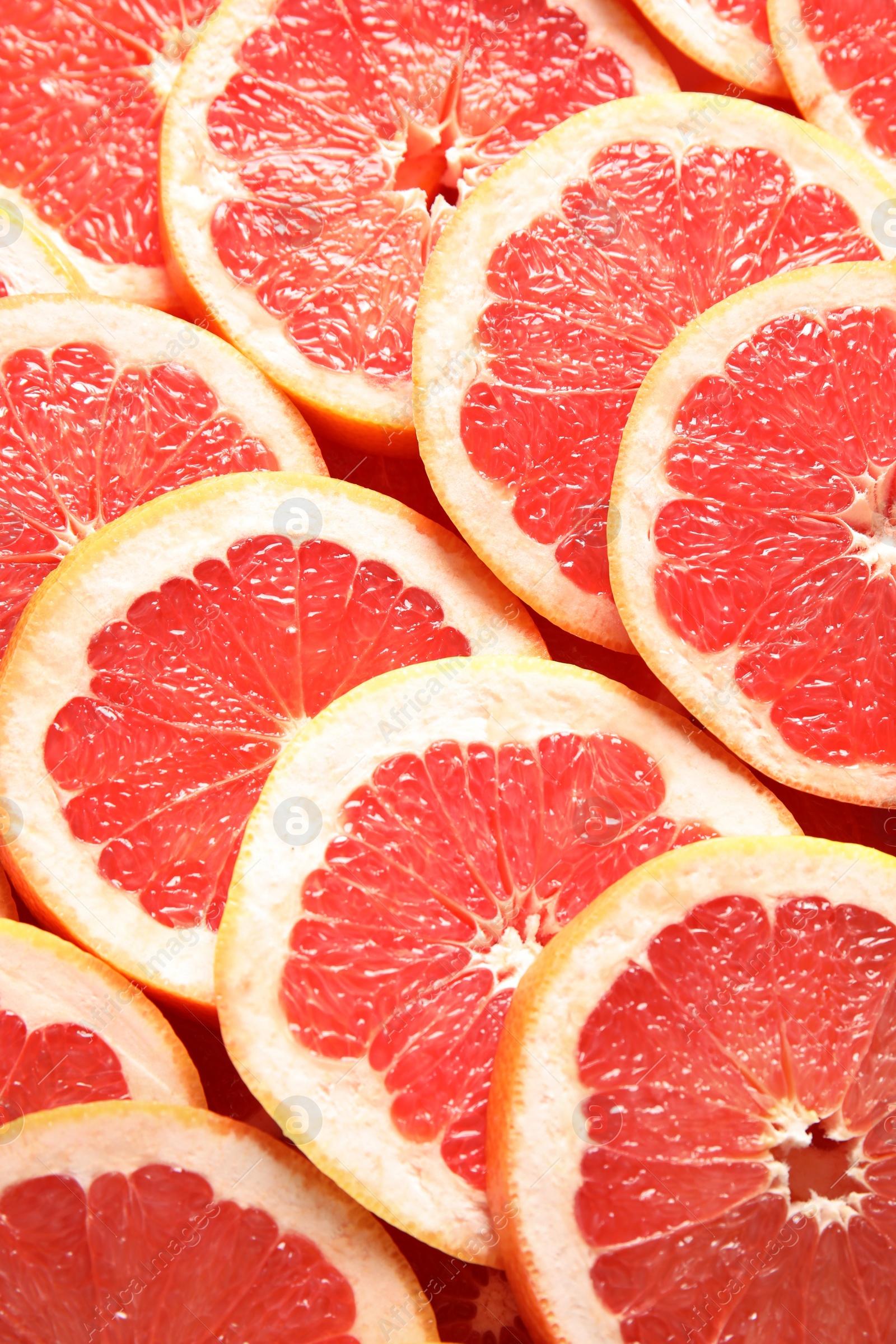 Photo of Many sliced fresh grapefruits as background, top view