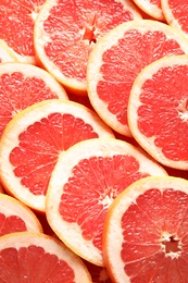 Many sliced fresh grapefruits as background, top view