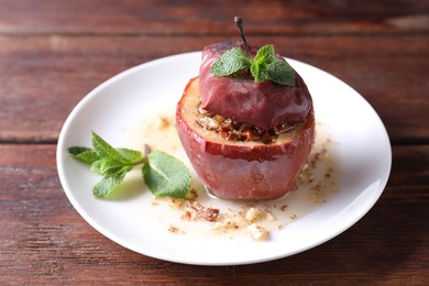 Tasty baked apple with nuts, honey and mint on wooden table, closeup