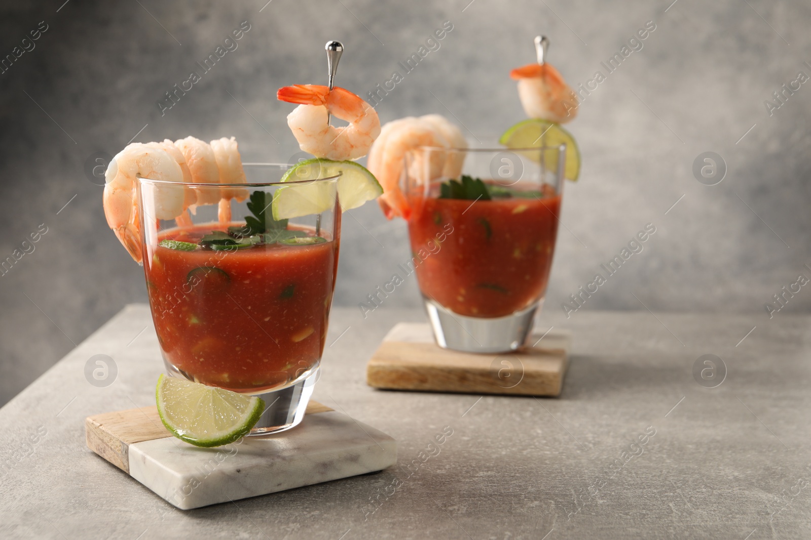 Photo of Tasty shrimp cocktail with sauce in glasses and lime on light grey table, space for text