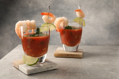 Tasty shrimp cocktail with sauce in glasses and lime on light grey table, space for text