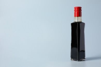 Photo of Bottle with soy sauce on light grey background, space for text