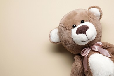 Cute teddy bear on beige background, top view. Space for text