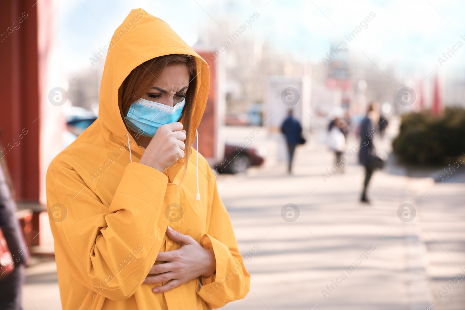 Photo of Woman with medical mask coughing on city street. Virus protection