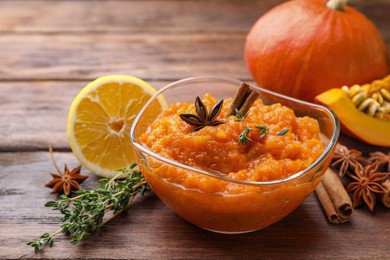 Bowl of delicious pumpkin jam and ingredients on wooden table, closeup
