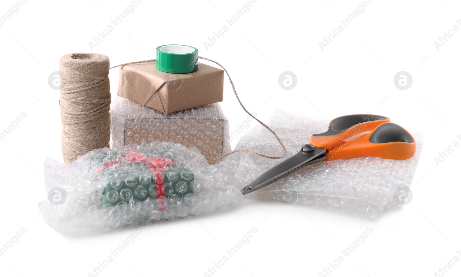 Photo of Cardboard boxes, bubble wrap, scissors and adhesive tape on white background