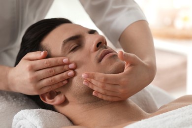 Photo of Man receiving facial massage in beauty salon, closeup