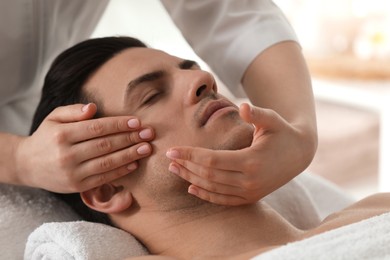 Man receiving facial massage in beauty salon, closeup