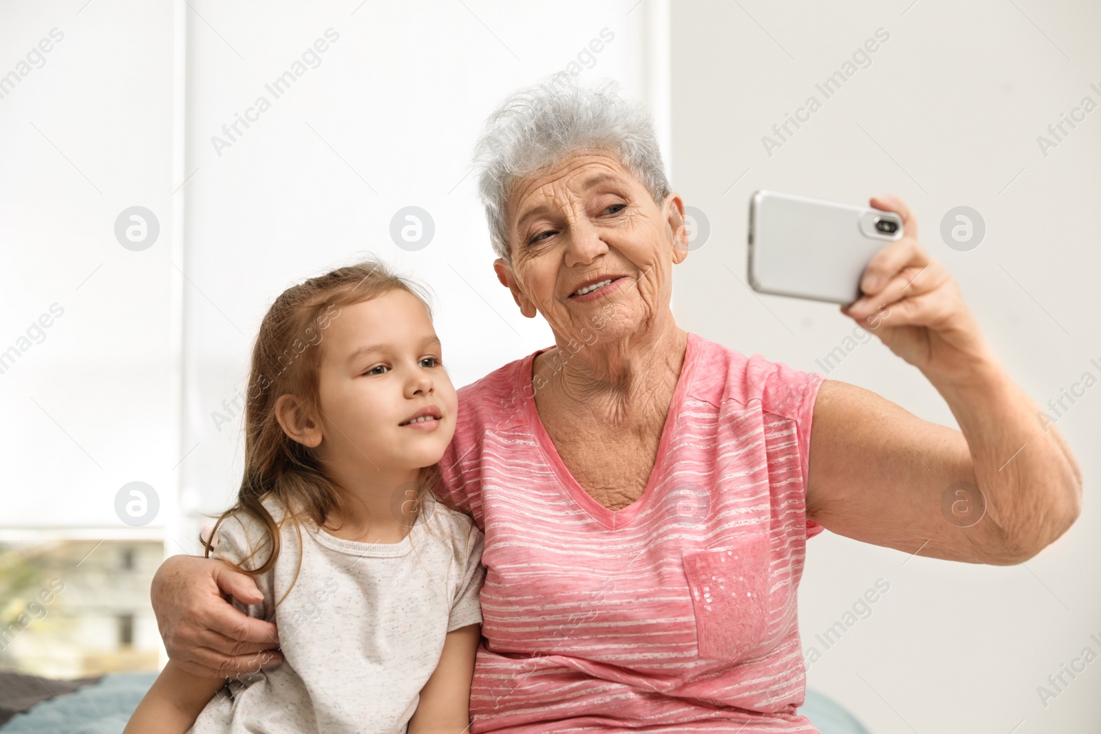 Photo of Cute girl and her grandmother taking selfie  at home