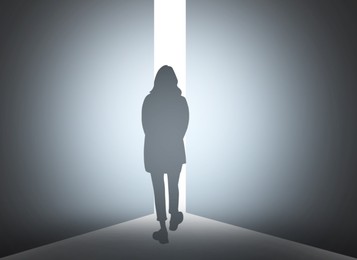 Image of Silhouette of woman standing in front of light hole, back view
