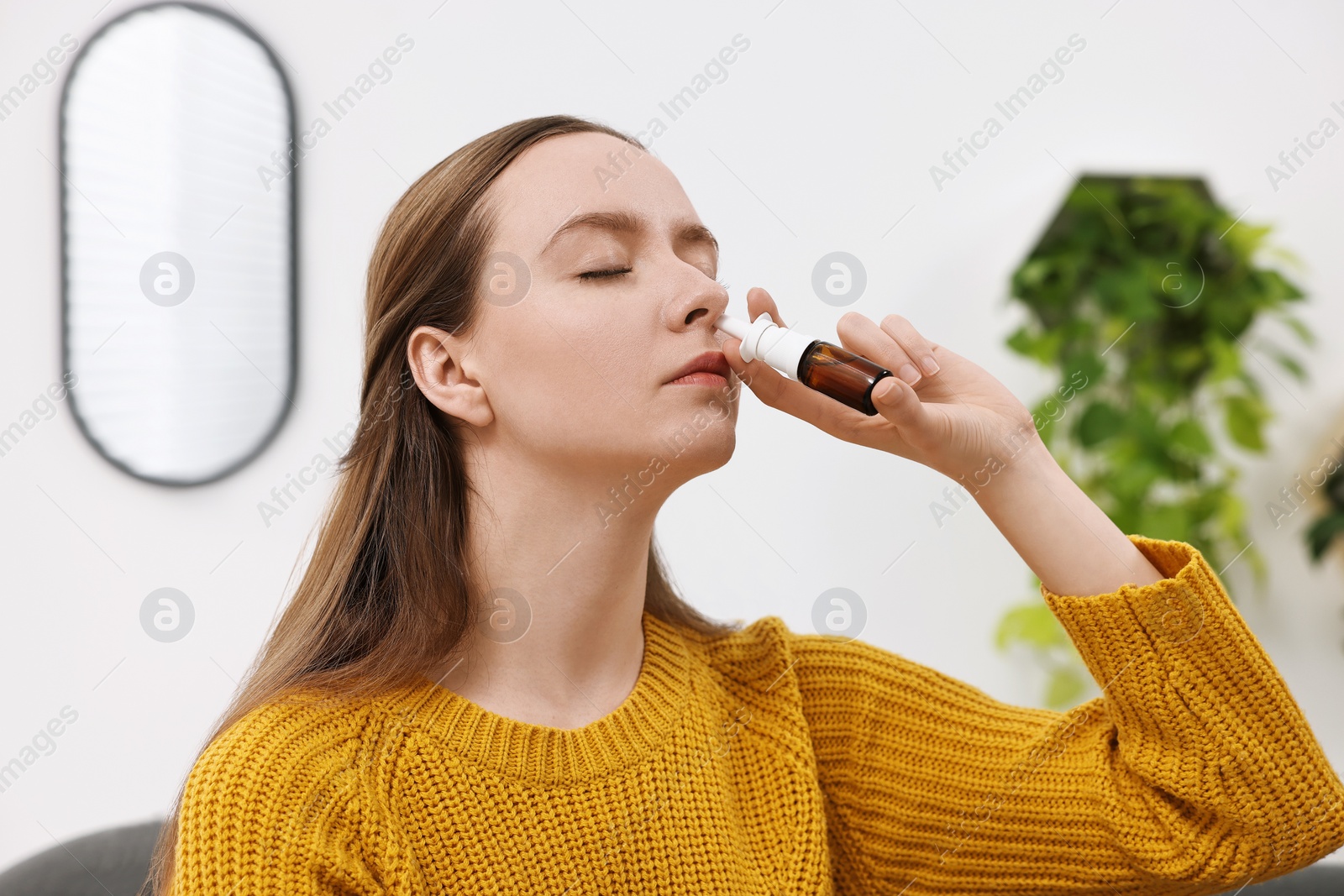 Photo of Medical drops. Young woman using nasal spray indoors