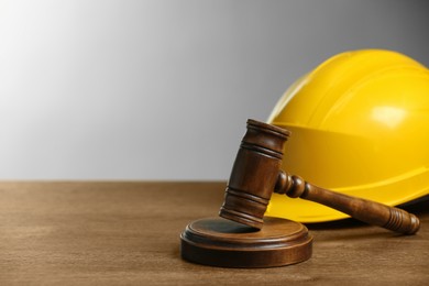 Photo of Construction and land law concepts. Gavel and hard hat on wooden table, space for text