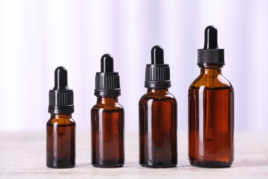 Photo of Bottles of essential oils on table against light background. Cosmetic products