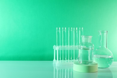 Laboratory analysis. Different glassware on table against green background, space for text