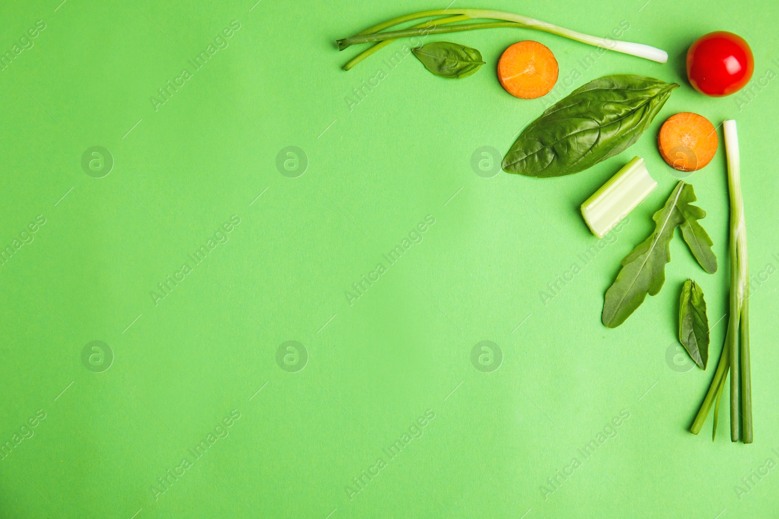 Photo of Flat lay composition with fresh salad ingredients on green background, space for text