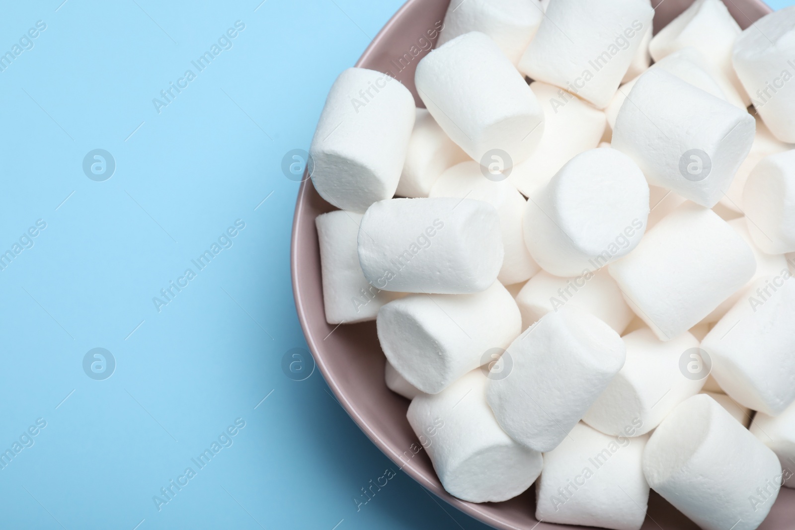 Photo of Delicious puffy marshmallows on light blue background, top view. Space for text