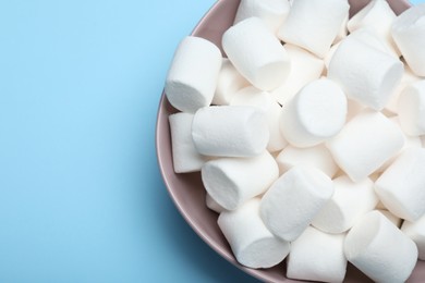 Delicious puffy marshmallows on light blue background, top view. Space for text