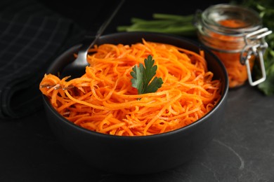 Photo of Delicious Korean carrot salad with parsley in bowl on black table