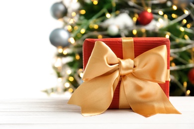 Beautiful gift box and blurred Christmas tree on background