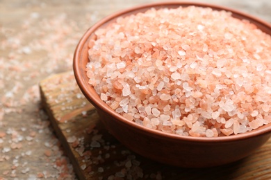 Photo of Pink himalayan salt in bowl on wooden table, closeup