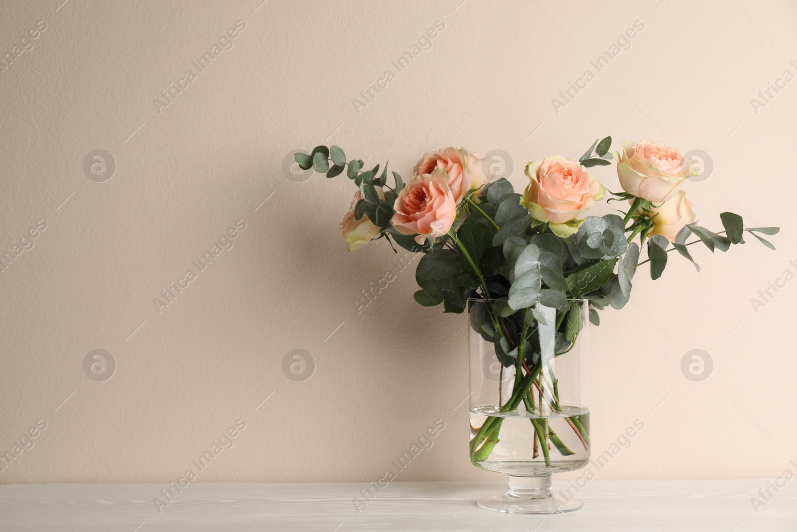 Photo of Vase with bouquet of beautiful roses on white wooden table. Space for text