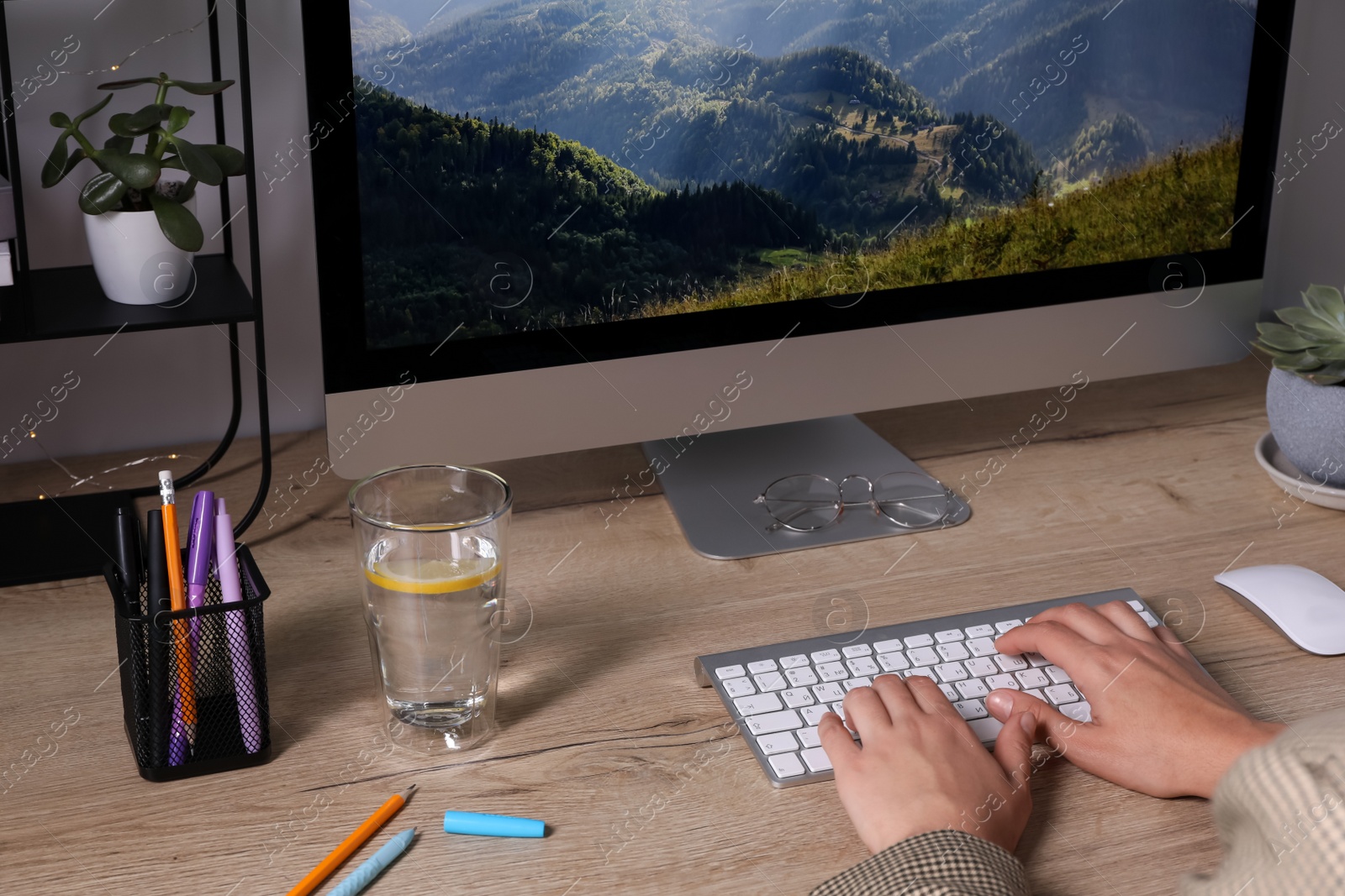 Photo of Woman working on computer at wooden table in room, closeup