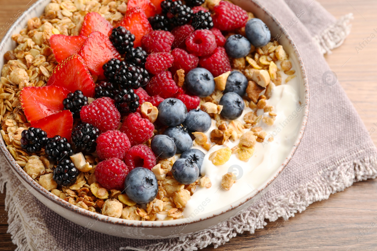 Photo of Healthy muesli served with berries on wooden table, closeup