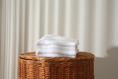 Photo of Soft terry towels on wicker basket indoors