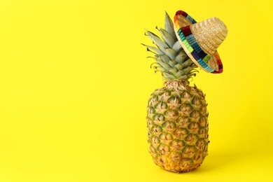 Pineapple with Mexican sombrero hat on yellow background, space for text