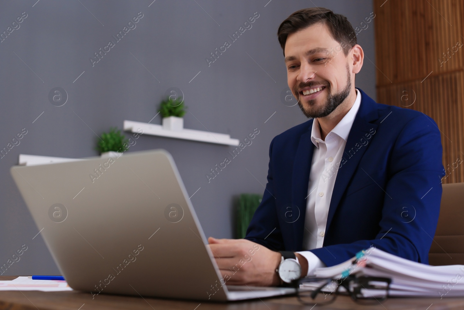 Photo of Businessman working with laptop and documents at table in office