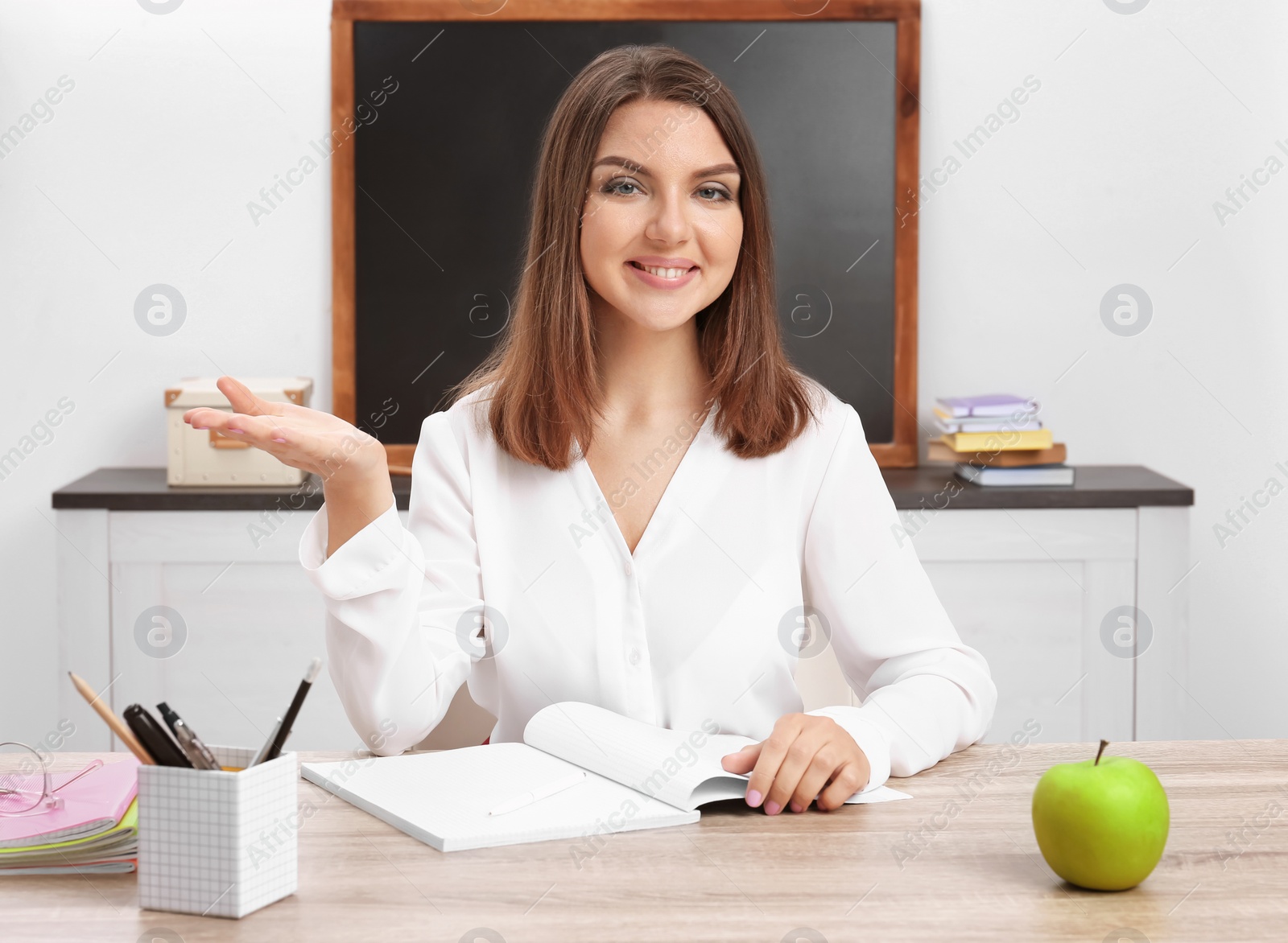 Photo of Portrait of female teacher sitting at table in classroom